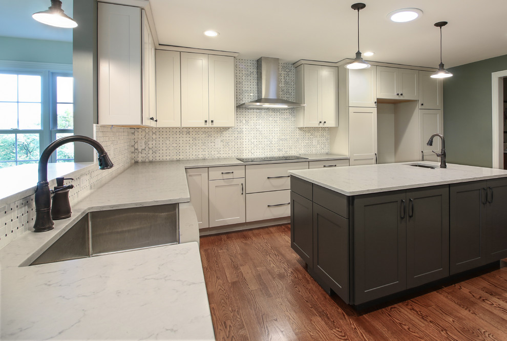 Transitional l-shaped eat-in kitchen in St Louis with an undermount sink, white cabinets, granite benchtops, multi-coloured splashback, ceramic splashback, stainless steel appliances, medium hardwood floors, with island, brown floor and white benchtop.