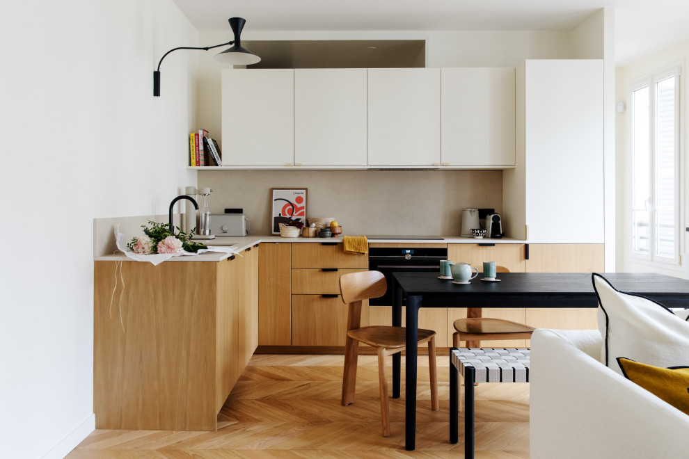 Small contemporary l-shaped open plan kitchen in Paris with an undermount sink, flat-panel cabinets, light wood cabinets, terrazzo benchtops, beige splashback, stone tile splashback, panelled appliances, medium hardwood floors, no island, brown floor and beige benchtop.