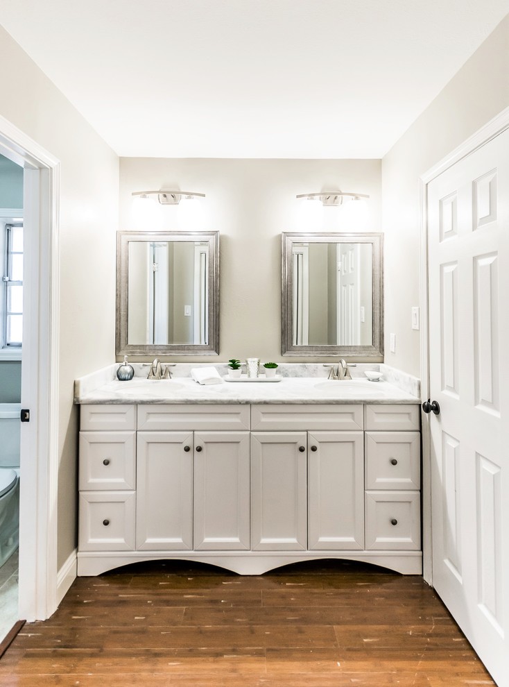 This is an example of a transitional master bathroom in New Orleans with shaker cabinets, white cabinets, grey walls, bamboo floors and marble benchtops.