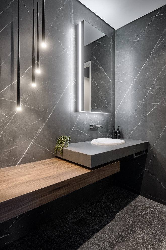 Inspiration for a large contemporary powder room in Perth with open cabinets, medium wood cabinets, a wall-mount toilet, black and white tile, pebble tile, terrazzo floors, a drop-in sink, engineered quartz benchtops, black floor, grey benchtops and a floating vanity.