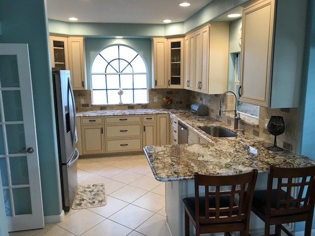 Mid-sized traditional u-shaped eat-in kitchen in Tampa with granite benchtops and travertine splashback.