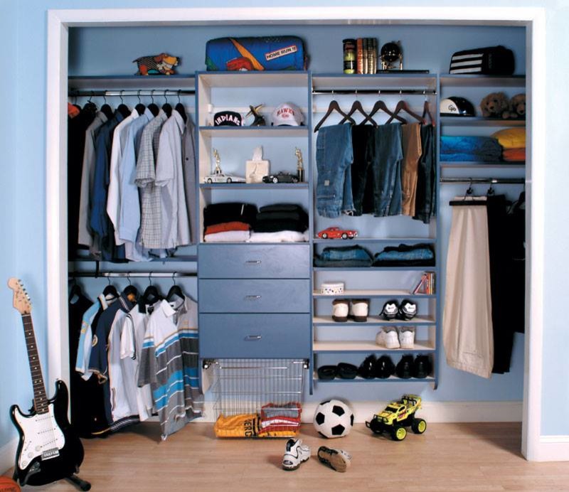Design ideas for a large traditional men's built-in wardrobe in New York with open cabinets, blue cabinets and light hardwood floors.