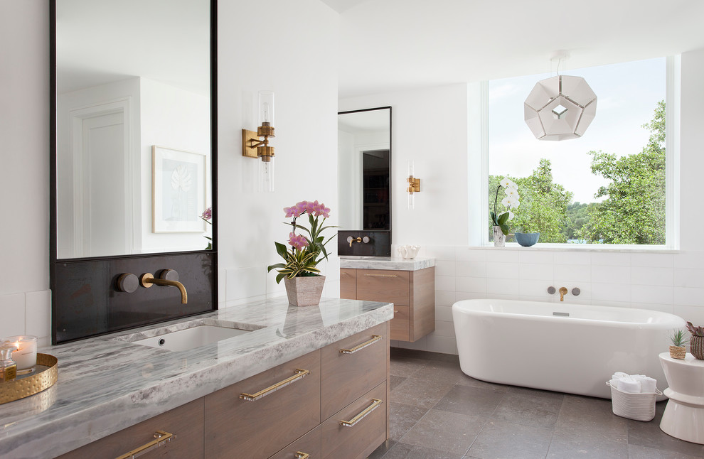 Contemporary master bathroom in Austin with flat-panel cabinets, medium wood cabinets, a freestanding tub, white tile, white walls, an undermount sink, grey floor and grey benchtops.