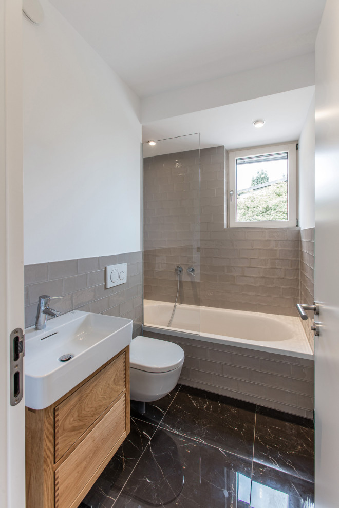 Modernes Badezimmer mit hellbraunen Holzschränken, grauem Boden, Einzelwaschbecken, Einbaubadewanne und Aufsatzwaschbecken in München