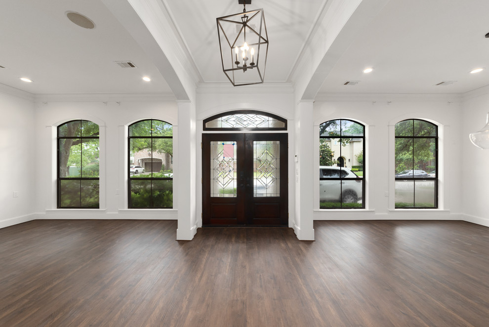 This is an example of a large transitional front door in Houston with white walls, laminate floors, a double front door, a dark wood front door and brown floor.
