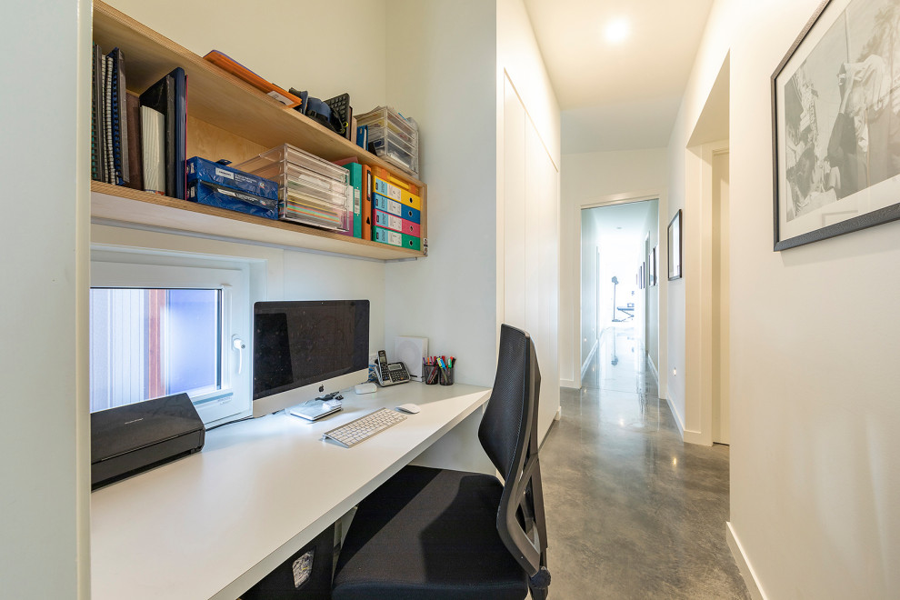 Photo of a small scandinavian home office in Canberra - Queanbeyan with white walls, concrete floors, a built-in desk and grey floor.