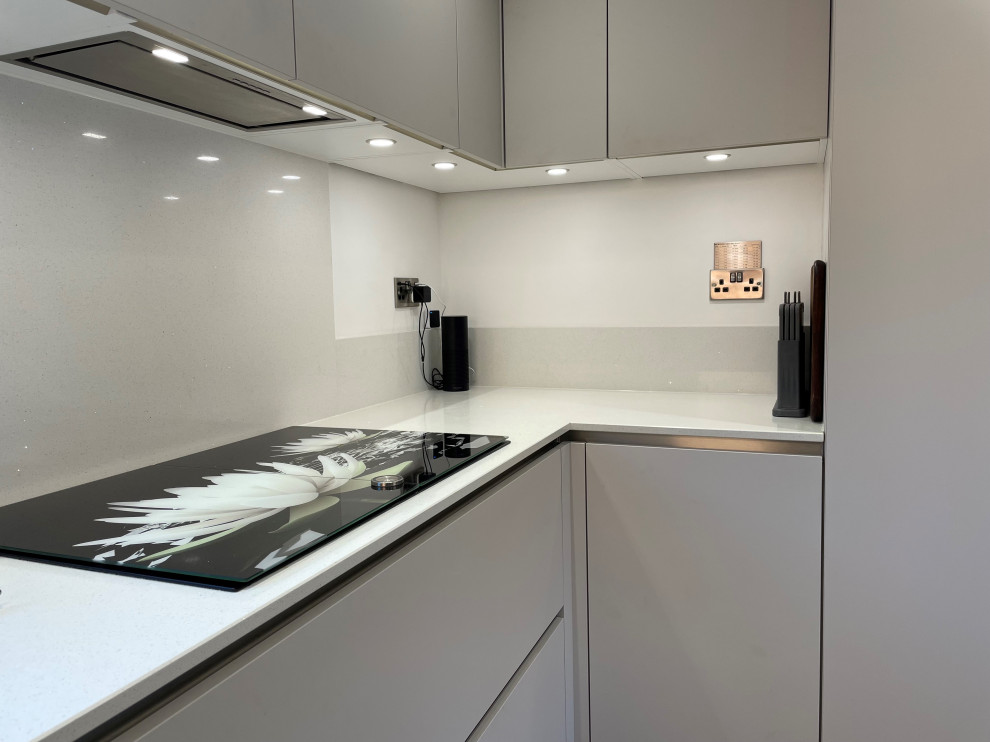 Design ideas for a medium sized contemporary u-shaped enclosed kitchen in Other with an integrated sink, flat-panel cabinets, quartz worktops, white splashback, medium hardwood flooring, no island and white worktops.