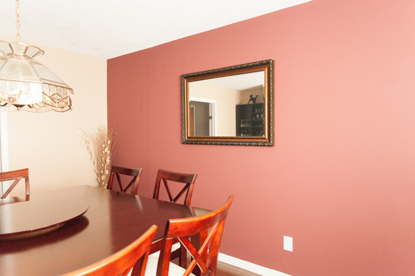 This is an example of a large transitional separate dining room in San Diego with pink walls, dark hardwood floors and no fireplace.