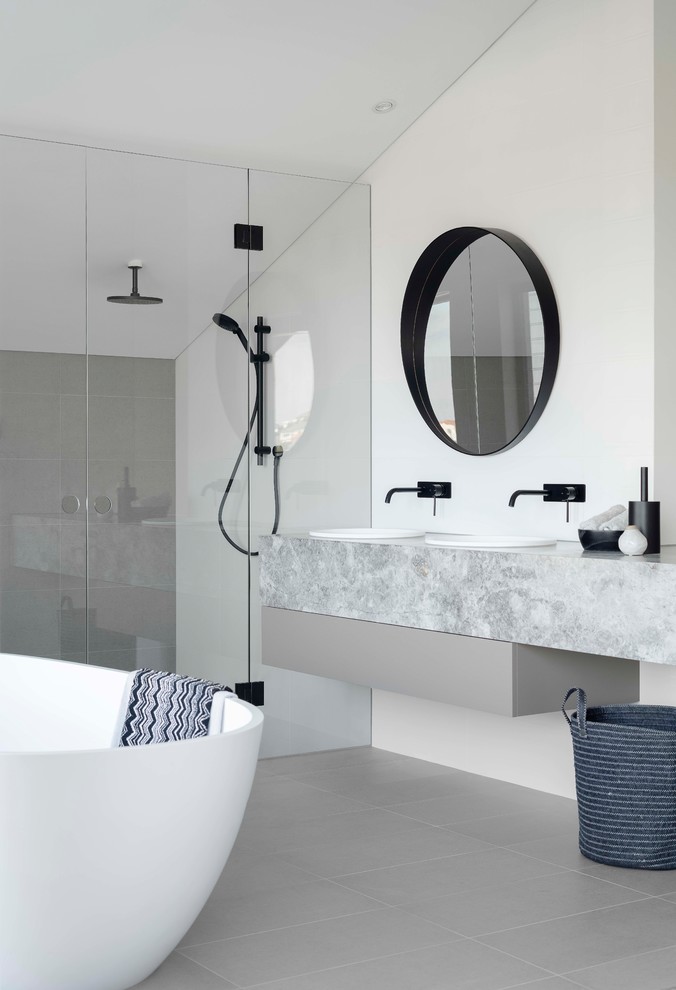 Inspiration for a large contemporary master bathroom in Sydney with flat-panel cabinets, grey cabinets, a freestanding tub, a double shower, a one-piece toilet, white tile, ceramic tile, white walls, ceramic floors, a drop-in sink, marble benchtops, grey floor, a hinged shower door and grey benchtops.