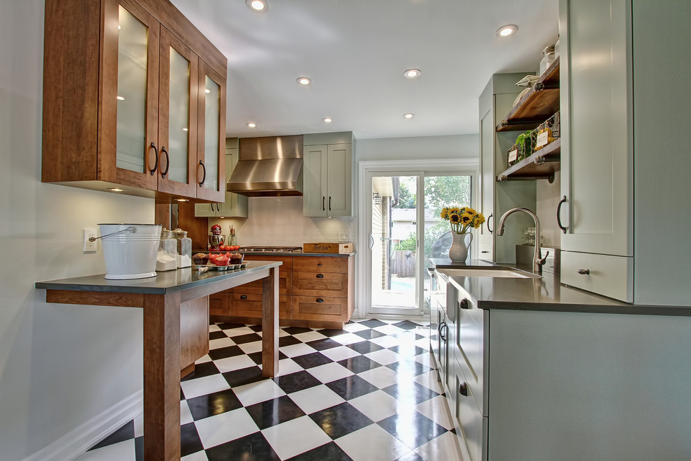 Large eclectic kitchen in Toronto with a farmhouse sink, recessed-panel cabinets, green cabinets, soapstone benchtops, white splashback, stainless steel appliances and ceramic floors.