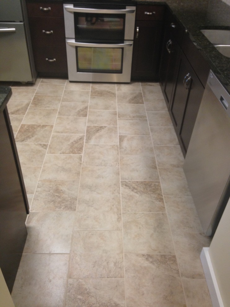 Mid-sized transitional l-shaped porcelain tile enclosed kitchen photo with an undermount sink, shaker cabinets, dark wood cabinets, granite countertops, beige backsplash, stone tile backsplash, stainless steel appliances and an island