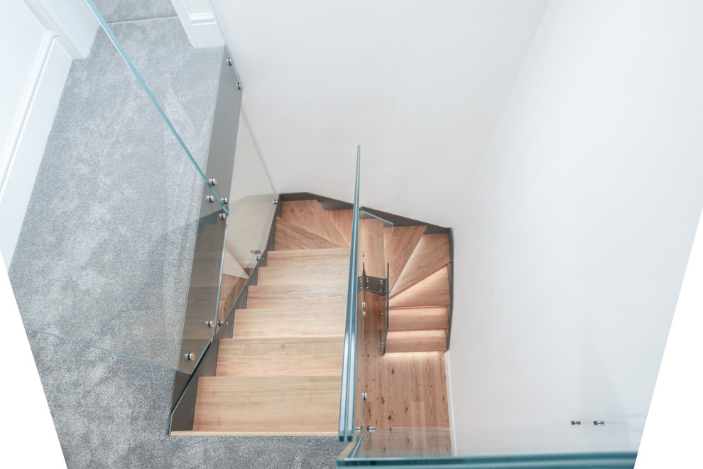 На фото: п-образная лестница среднего размера в стиле модернизм с деревянными ступенями и стеклянными перилами без подступенок