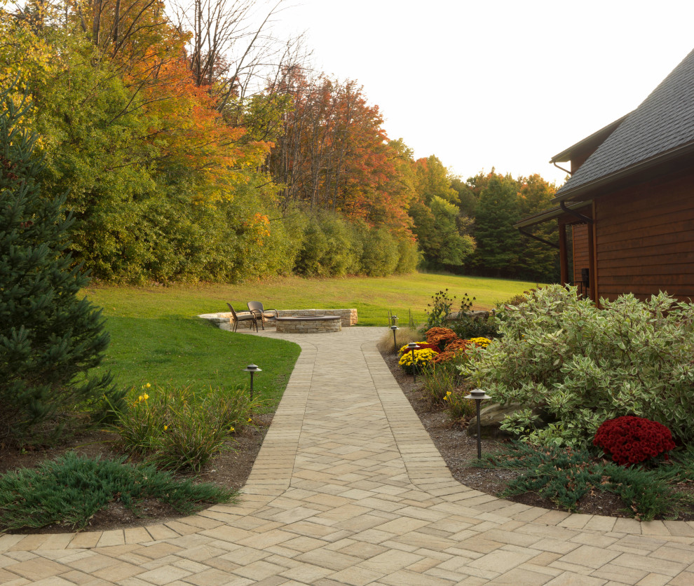 Expansive rural back full sun garden in Burlington with a fire feature and concrete paving.