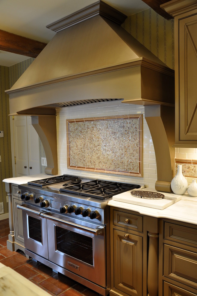 Photo of a country eat-in kitchen in New York with a farmhouse sink, raised-panel cabinets, dark wood cabinets, marble benchtops, white splashback, mosaic tile splashback and panelled appliances.
