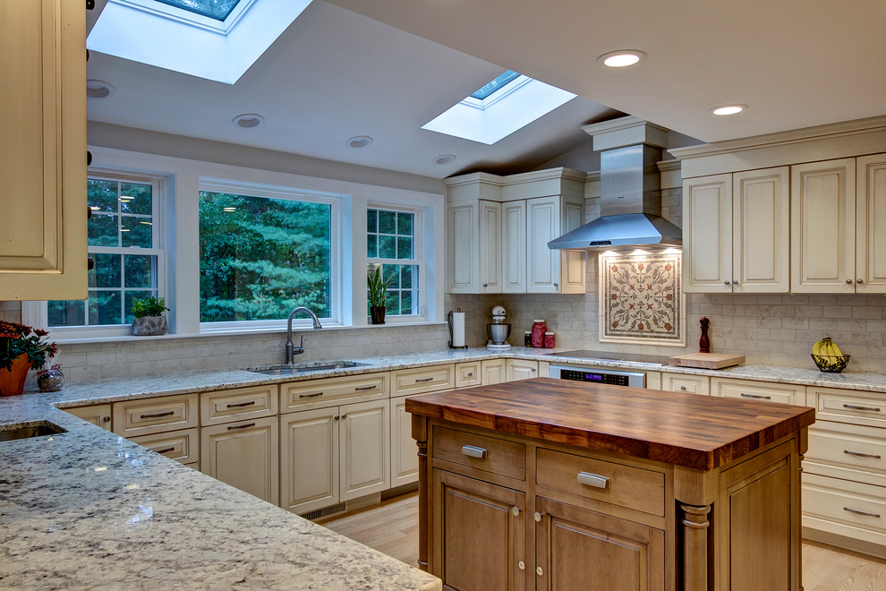 Photo of a large transitional u-shaped eat-in kitchen in Boston with an undermount sink, raised-panel cabinets, distressed cabinets, granite benchtops, beige splashback, porcelain splashback, stainless steel appliances, light hardwood floors and multiple islands.