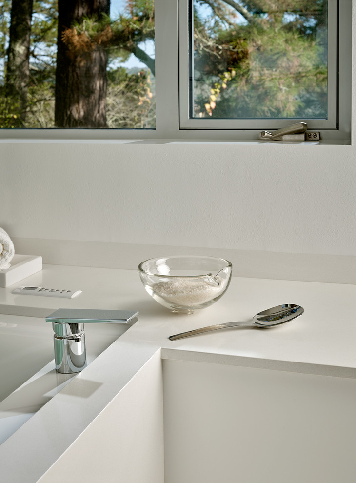 Photo of a large contemporary master bathroom in San Francisco with flat-panel cabinets, white cabinets, an alcove tub, an alcove shower, a wall-mount toilet, white tile, porcelain tile, white walls, porcelain floors, an undermount sink and solid surface benchtops.