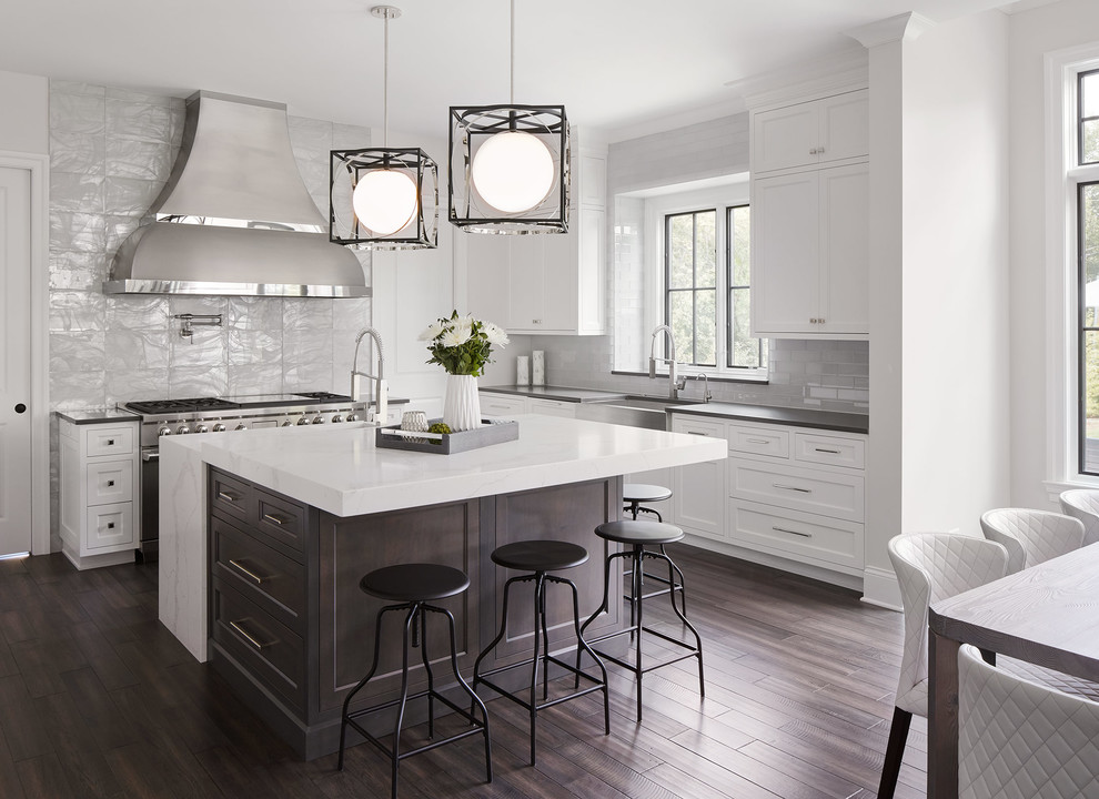 Inspiration for a transitional l-shaped eat-in kitchen in Chicago with a farmhouse sink, shaker cabinets, white cabinets, grey splashback, subway tile splashback, stainless steel appliances, dark hardwood floors and with island.