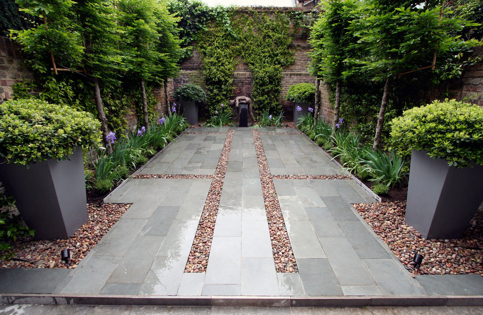 Inspiration for a contemporary backyard patio in London with natural stone pavers and no cover.
