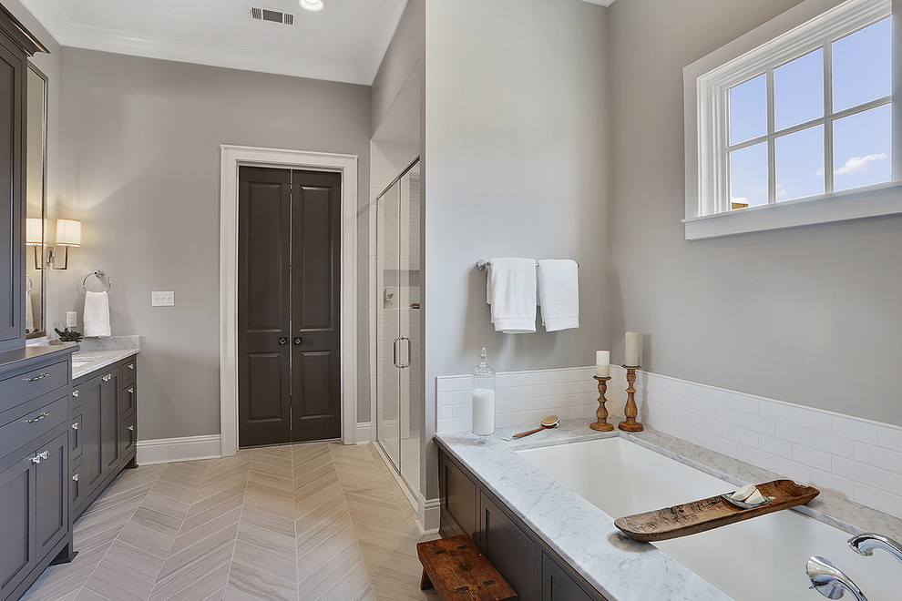 Large traditional master bathroom in New Orleans with recessed-panel cabinets, grey cabinets, a drop-in tub, a double shower, white tile, ceramic tile, grey walls, porcelain floors, a drop-in sink and marble benchtops.