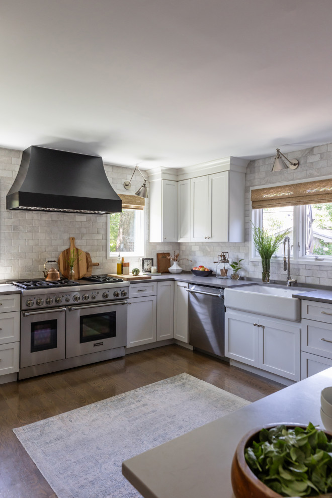 Inspiration for a mid-sized transitional u-shaped medium tone wood floor and brown floor open concept kitchen remodel in Chicago with a farmhouse sink, shaker cabinets, white cabinets, quartz countertops, white backsplash, marble backsplash, stainless steel appliances, an island and gray countertops