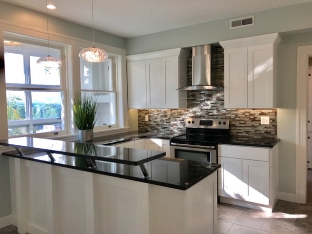 Photo of a mid-sized transitional u-shaped separate kitchen in Cleveland with an undermount sink, recessed-panel cabinets, black cabinets, quartz benchtops, multi-coloured splashback, matchstick tile splashback, stainless steel appliances, porcelain floors, a peninsula, brown floor and blue benchtop.