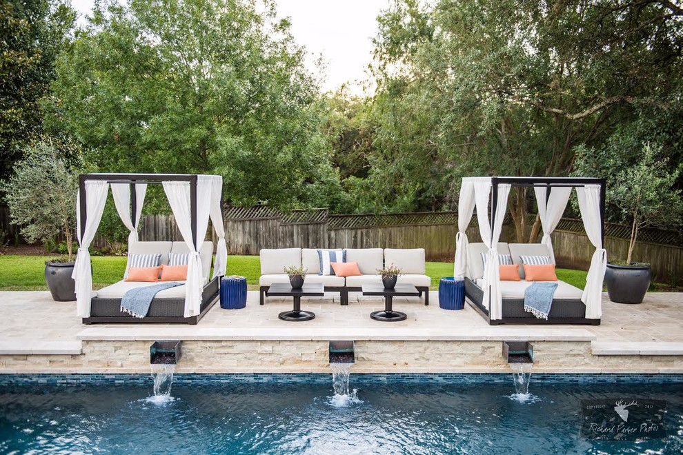 This is an example of a large transitional backyard pool in Austin with concrete pavers and a water feature.