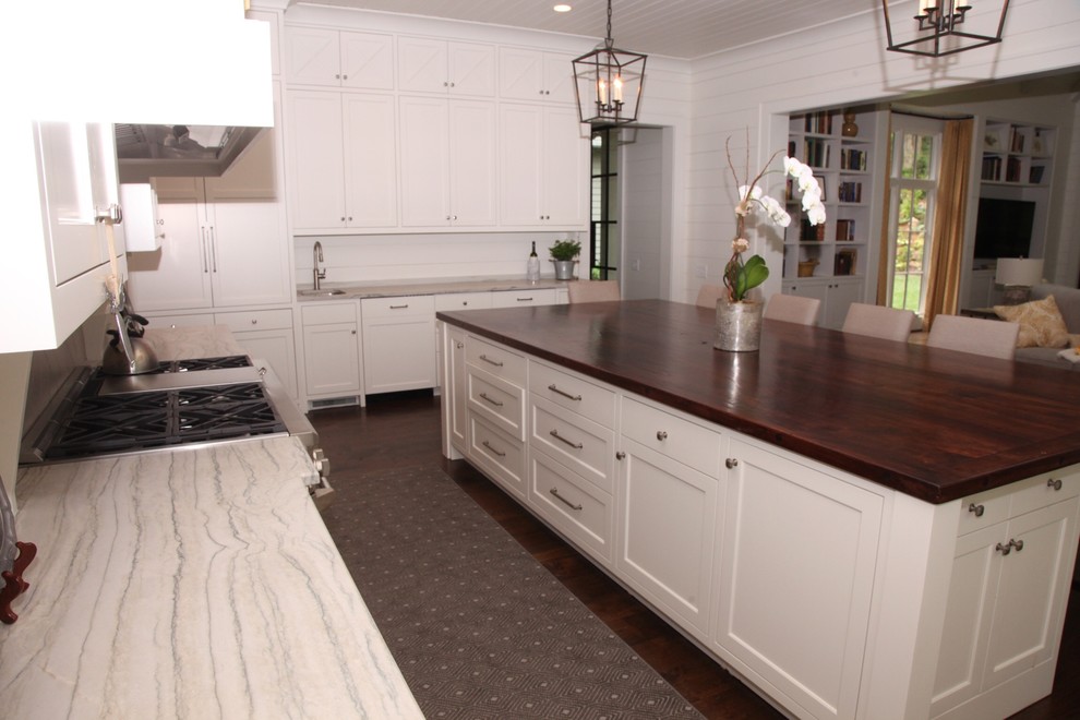 Mid-sized transitional l-shaped open plan kitchen in Atlanta with an undermount sink, white cabinets, quartzite benchtops, stainless steel appliances, dark hardwood floors, with island, brown floor and recessed-panel cabinets.