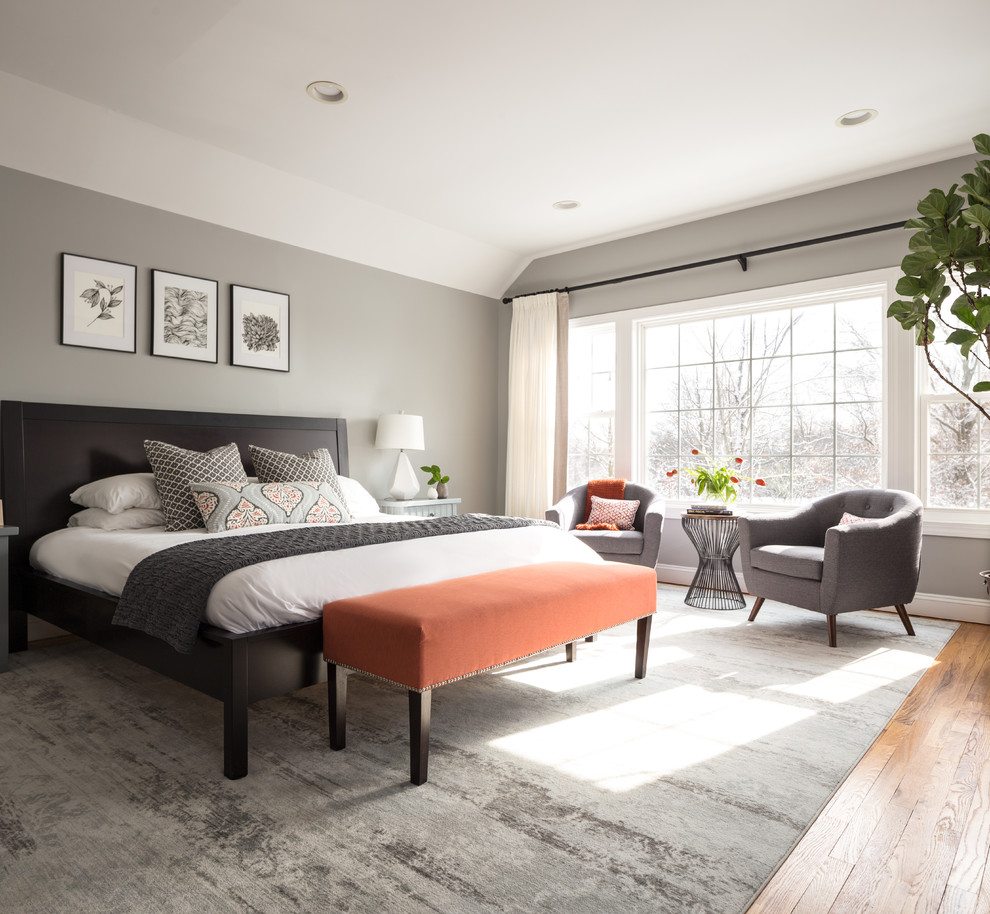 Inspiration for a large transitional master bedroom in New York with grey walls, medium hardwood floors, a standard fireplace, a stone fireplace surround and grey floor.