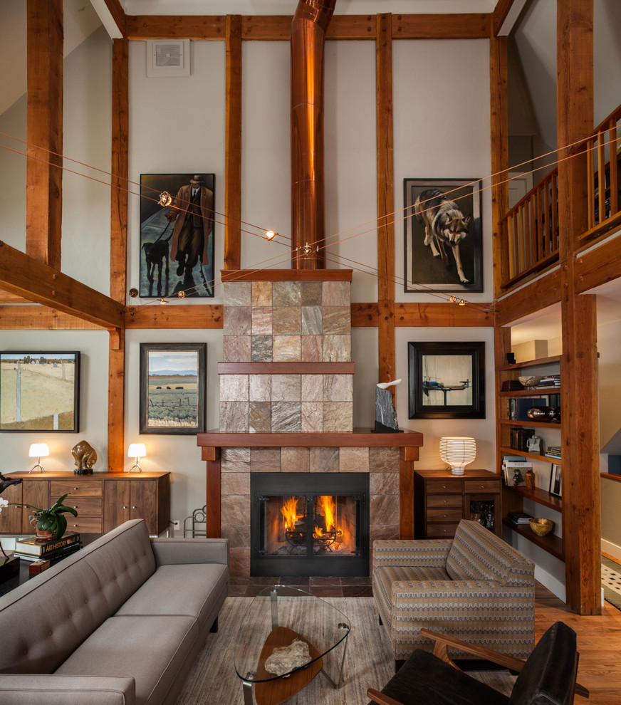Inspiration for a country open concept living room in Denver with white walls, medium hardwood floors, a standard fireplace, a stone fireplace surround and brown floor.