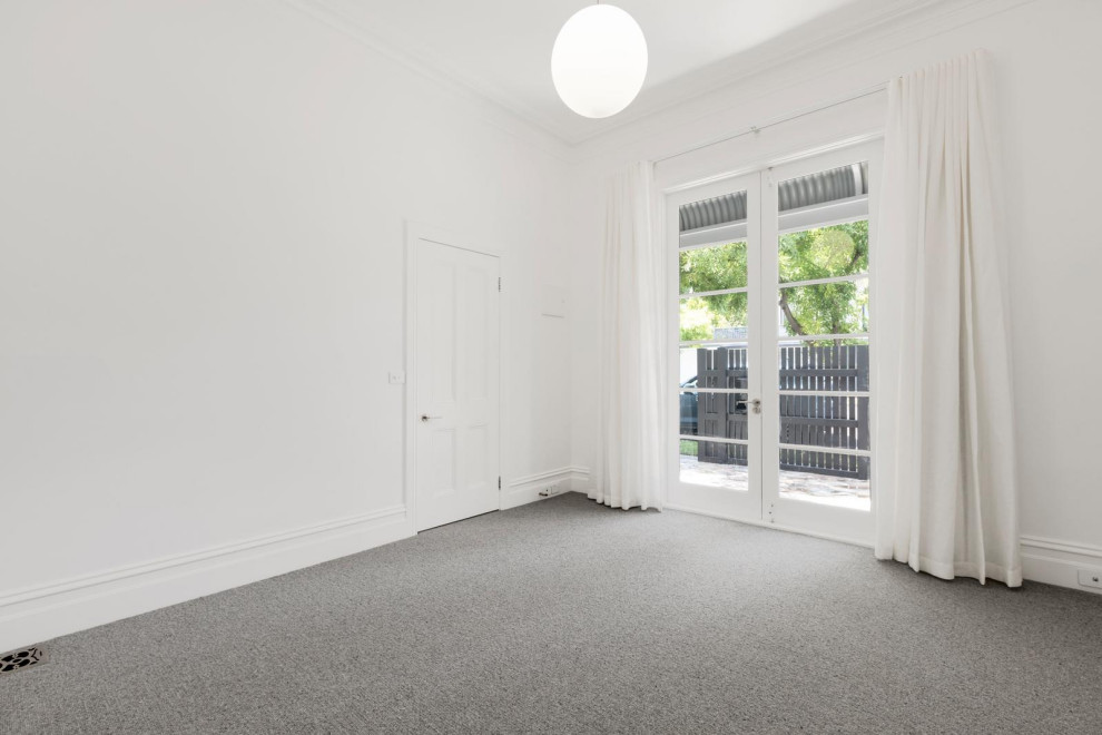 Mittelgroßes Nordisches Hauptschlafzimmer mit weißer Wandfarbe, Teppichboden, Kamin, Kaminumrandung aus Stein und grauem Boden in Melbourne