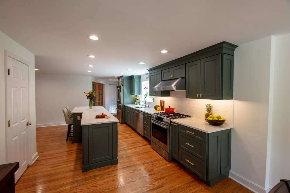 Small galley eat-in kitchen in Philadelphia with an undermount sink, recessed-panel cabinets, grey cabinets, quartz benchtops, white splashback, porcelain splashback, stainless steel appliances, light hardwood floors, with island, brown floor and white benchtop.