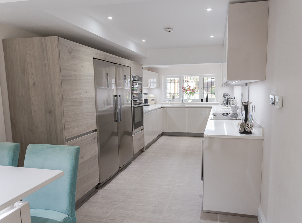 Inspiration for a mid-sized modern u-shaped eat-in kitchen in Hertfordshire with flat-panel cabinets, light wood cabinets, quartzite benchtops, stainless steel appliances and white benchtop.
