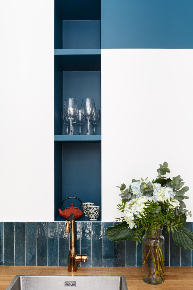 Источник вдохновения для домашнего уюта: маленькая угловая кухня-гостиная в современном стиле с одинарной мойкой, плоскими фасадами, синими фасадами, деревянной столешницей, синим фартуком, фартуком из керамической плитки, техникой под мебельный фасад, полом из терраццо, разноцветным полом и коричневой столешницей для на участке и в саду