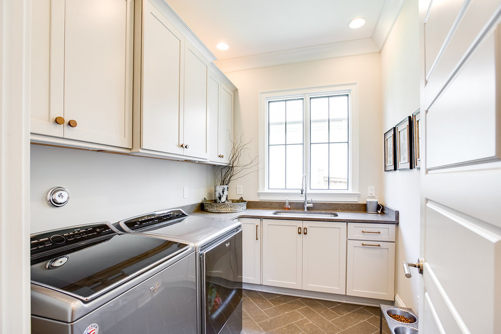 Photo of a mid-sized traditional galley laundry cupboard in Birmingham with an undermount sink, flat-panel cabinets, grey cabinets, limestone benchtops, white walls, limestone floors, a side-by-side washer and dryer and grey benchtop.