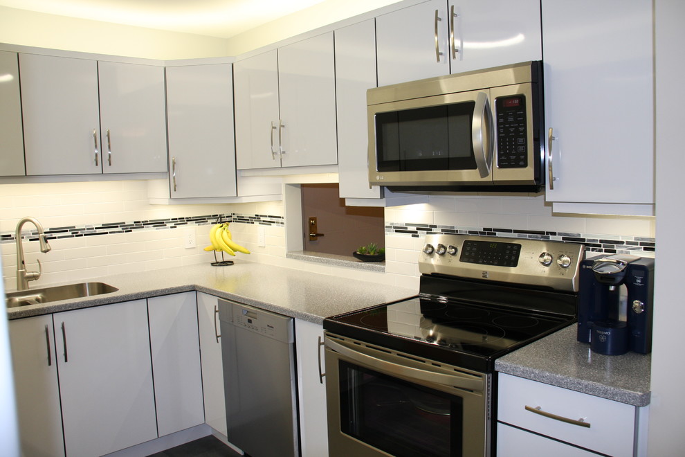 Example of a small minimalist u-shaped porcelain tile enclosed kitchen design in Edmonton with a drop-in sink, flat-panel cabinets, white cabinets, laminate countertops, white backsplash, ceramic backsplash, white appliances and no island