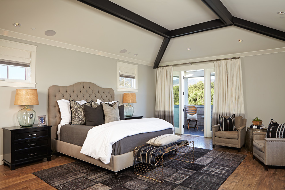 This is an example of a large transitional master bedroom in Orange County with grey walls and medium hardwood floors.