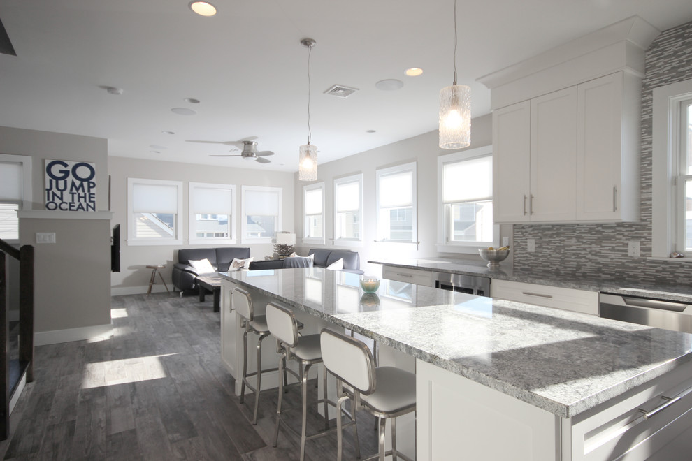 This is an example of a large beach style u-shaped open plan kitchen in New York with white cabinets, multi-coloured splashback, ceramic splashback, vinyl floors and with island.
