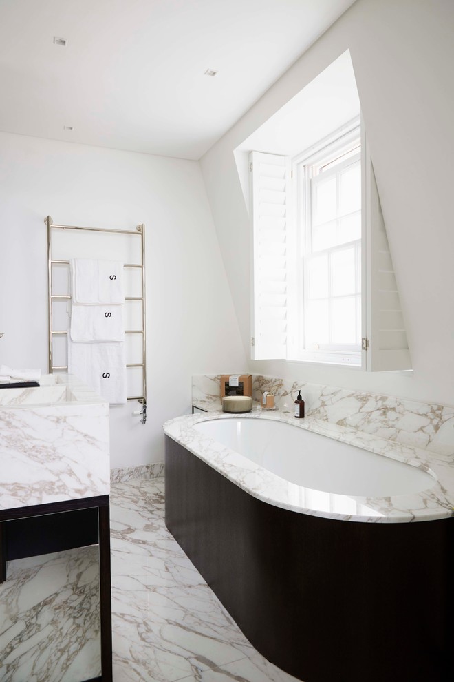 Design ideas for a mid-sized transitional master bathroom in London with white walls, marble floors and an undermount tub.