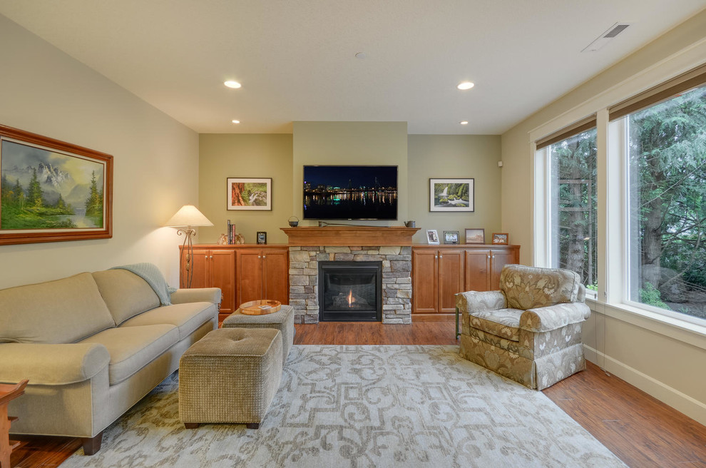 Mid-sized arts and crafts open concept living room in Portland with green walls, medium hardwood floors, a standard fireplace, a stone fireplace surround and a wall-mounted tv.
