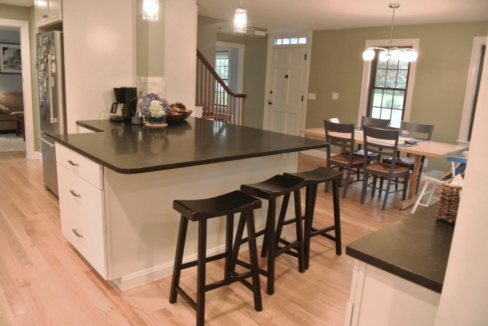 Eat-in kitchen - transitional u-shaped light wood floor eat-in kitchen idea in Boston with shaker cabinets, a peninsula, an undermount sink, white cabinets, beige backsplash, porcelain backsplash, stainless steel appliances and black countertops