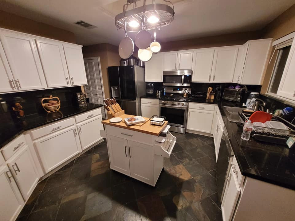 Immagine di una cucina bohémian di medie dimensioni con lavello a doppia vasca, ante con riquadro incassato, ante gialle, paraspruzzi nero, elettrodomestici in acciaio inossidabile, pavimento in ardesia, pavimento nero e top nero