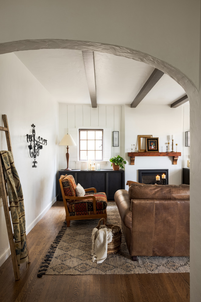 Mittelgroßes, Abgetrenntes Wohnzimmer mit weißer Wandfarbe, braunem Holzboden, Kamin, verputzter Kaminumrandung, freigelegten Dachbalken und Wandpaneelen in Sacramento