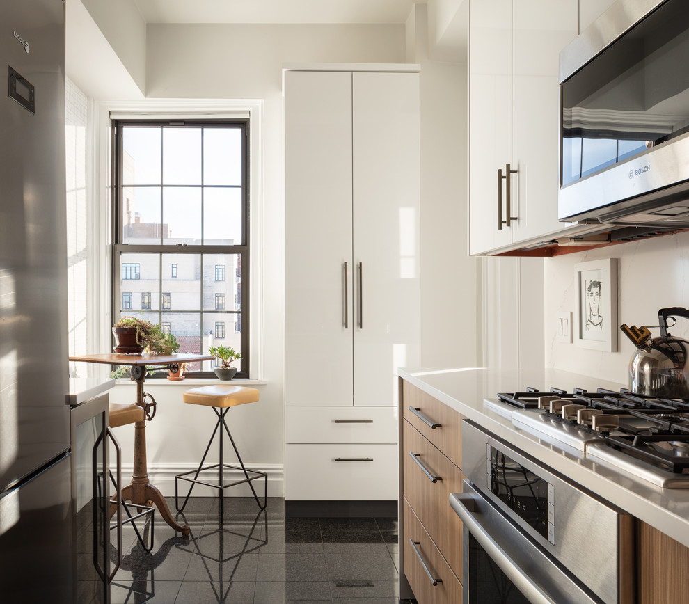 Design ideas for a small transitional u-shaped eat-in kitchen in New York with an undermount sink, flat-panel cabinets, light wood cabinets, quartz benchtops, white splashback, marble splashback, stainless steel appliances, ceramic floors, no island, black floor and grey benchtop.