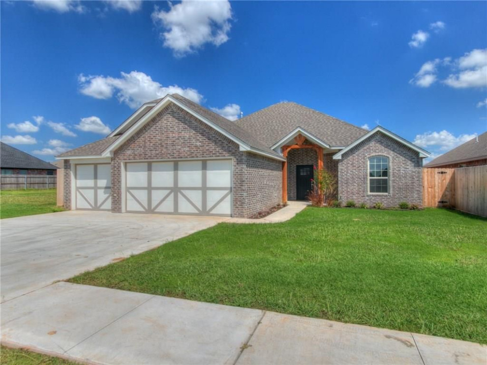 3 car garage with brick and neutral colors