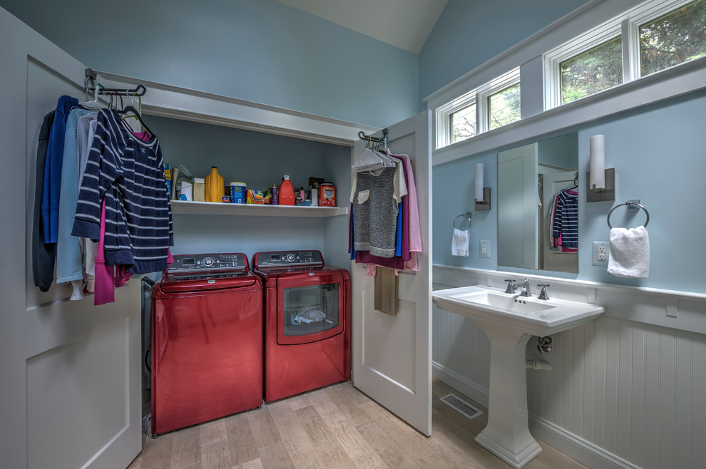 Design ideas for a mid-sized transitional single-wall utility room in DC Metro with blue walls, light hardwood floors and a concealed washer and dryer.