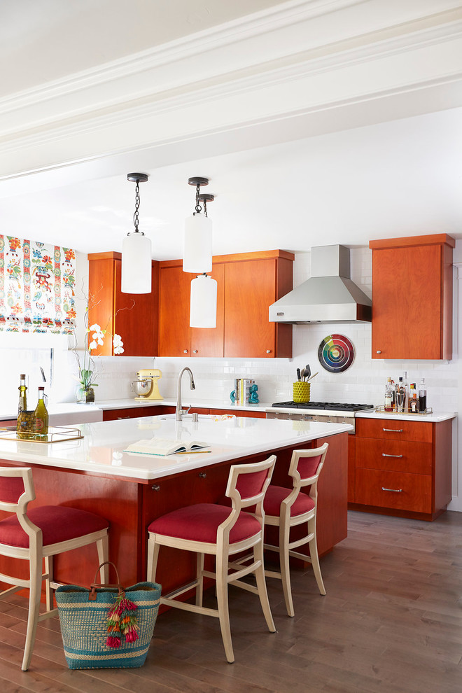 Photo of a mid-sized transitional u-shaped kitchen in Sacramento with a farmhouse sink, flat-panel cabinets, orange cabinets, white splashback, with island, subway tile splashback and stainless steel appliances.