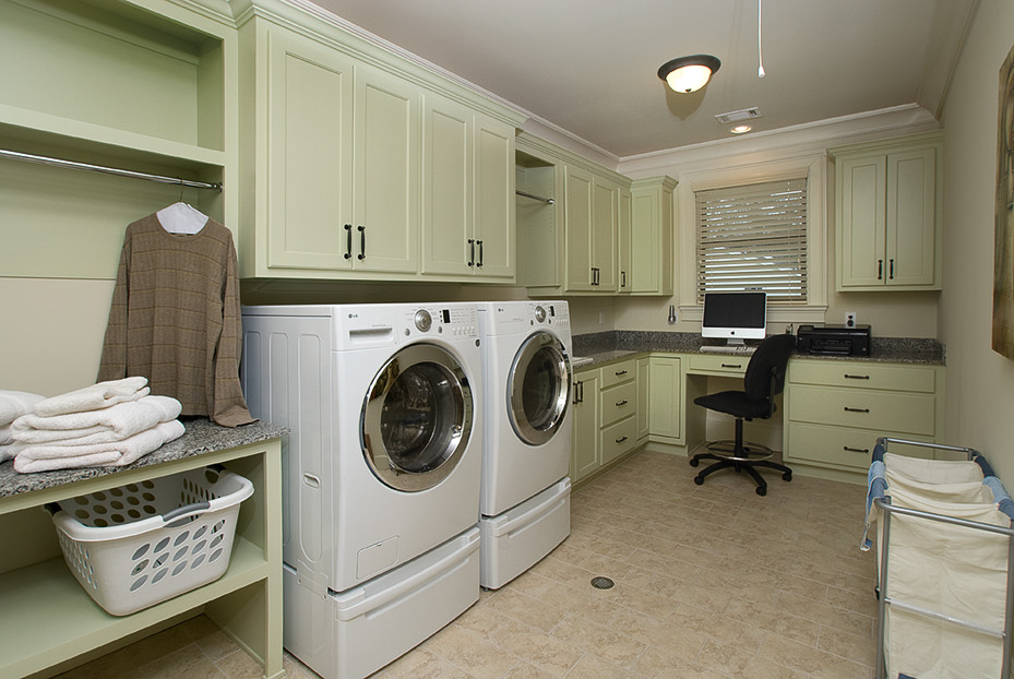 Photo of an expansive transitional l-shaped utility room in Atlanta with a drop-in sink, flat-panel cabinets, green cabinets, granite benchtops, beige walls, ceramic floors, a side-by-side washer and dryer, beige floor and brown benchtop.