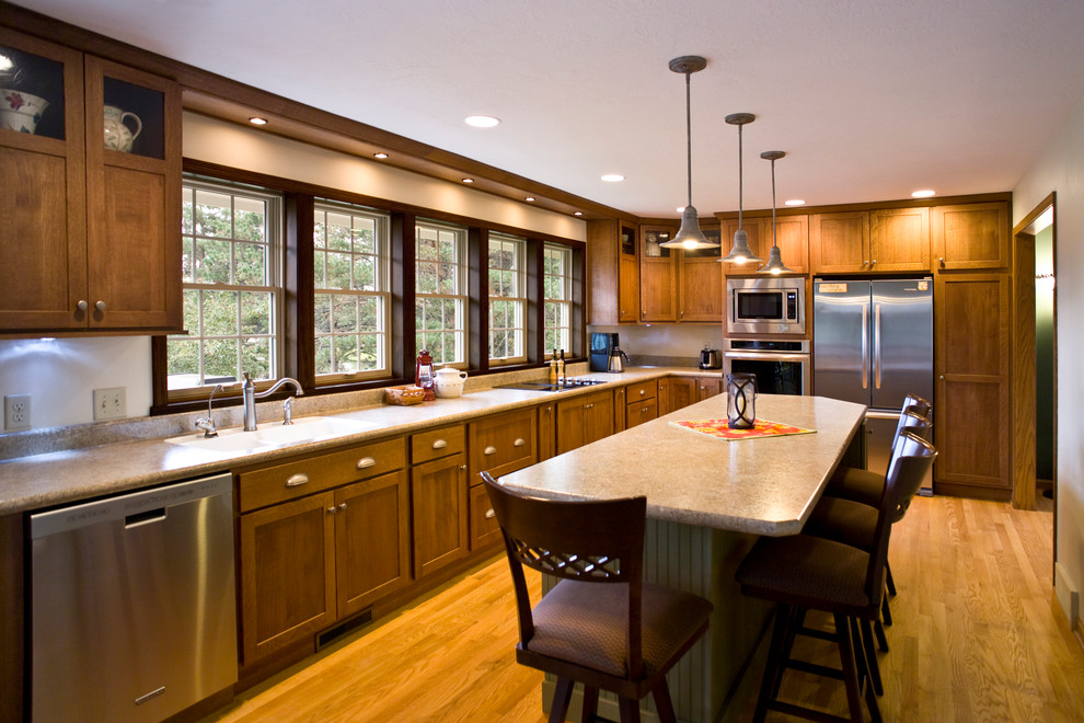 Eat-in kitchen - mid-sized transitional l-shaped light wood floor and brown floor eat-in kitchen idea with a drop-in sink, raised-panel cabinets, medium tone wood cabinets, granite countertops, stainless steel appliances and an island