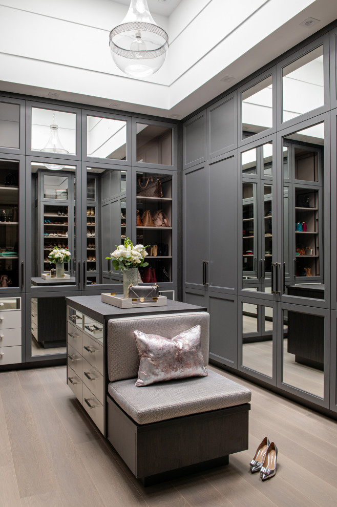 Design ideas for a medium sized traditional gender neutral built-in wardrobe in Toronto with glass-front cabinets, grey cabinets, medium hardwood flooring and brown floors.