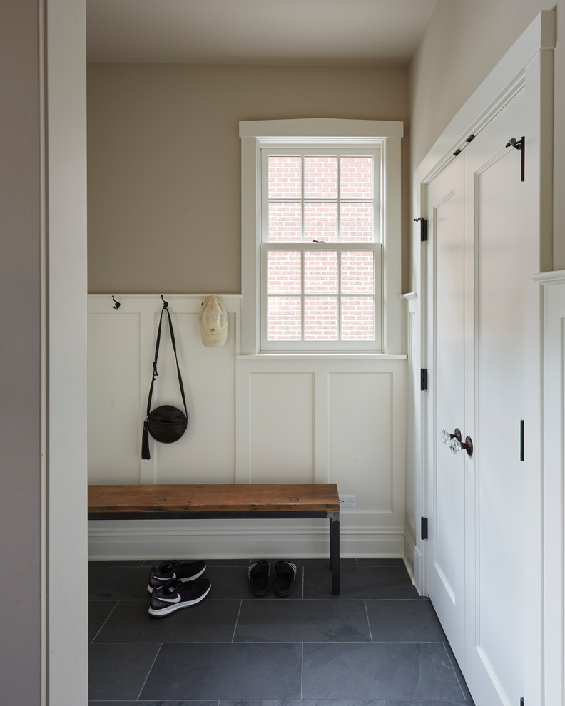 Design ideas for a mid-sized transitional mudroom in Other with beige walls and black floor.